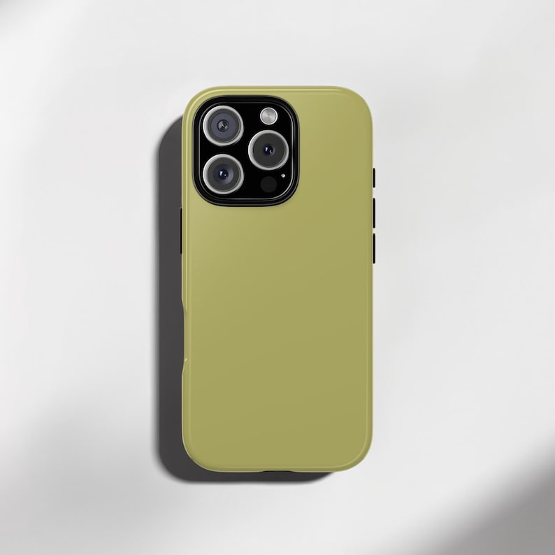 May include: A light olive green phone case with a triple-lens camera system. The case has a smooth, matte finish and a black accent on the side. The phone case is designed to protect the phone from scratches and damage.