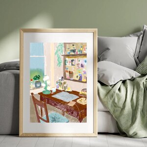Op de afbeelding: Een ingelijste kunstdruk toont een gezellige interieurscène. Een houten bureau met een blauwe blotter, stoel en raam met uitzicht zijn te zien. Een plank met diverse items is zichtbaar. Het kleurenpalet omvat bruin, blauw en groen.