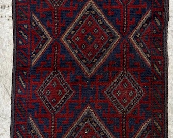 May include: A rectangular runner rug featuring a deep red and navy blue color palette. The design consists of a repeating pattern of geometric diamond shapes with intricate interior detailing, framed by horizontal striped borders with fringe ends.