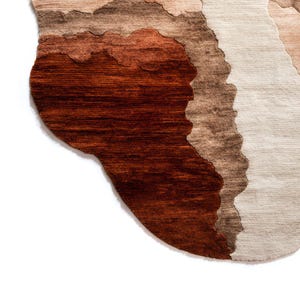 A close-up of the bottom left corner of the irregular rug, showing dark brown, light brown, and beige wavy sections.