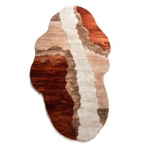 A vertically oriented irregular-shaped rug with wavy sections of dark brown, light brown, beige, and terracotta colors.