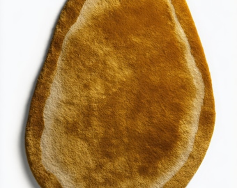 Alfombra de forma irregular en lana color ocre dorado, con diseño de forma libre tejido a mano.