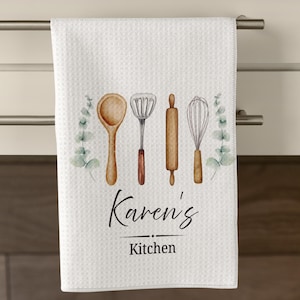 May include: White kitchen towel with a waffle weave texture, featuring watercolor illustrations of kitchen utensils and eucalyptus sprigs. The text "Karen's Kitchen" is displayed in elegant script. A decorative and functional kitchen accessory.