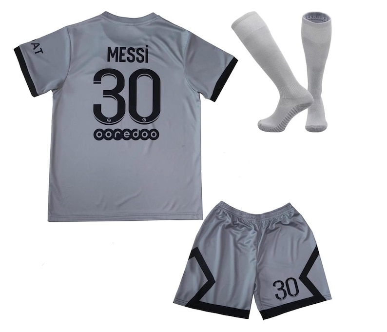 May include: A gray soccer uniform set featuring a jersey with "MESSI 30" and "ooredoo" printed on the back, matching shorts with the number 30, and a pair of gray socks. The jersey and shorts have black trim.