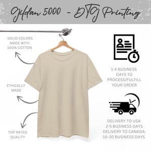 Puede incluir: Una camiseta beige Gildan 5000 cuelga de una percha de madera. La camiseta est&aacute; hecha de 100% algod&oacute;n y est&aacute; fabricada &eacute;ticamente. La imagen incluye el texto "DTG Printing" y "Top Rated Quality".