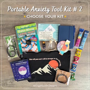 May include: A black zippered pouch with a mountain and sun graphic and the text This will pass and I will be stronger on the other side. Included are a crossword book, blue notebook, steam eye masks, fidget spinner, essential oil, and drink mixes.