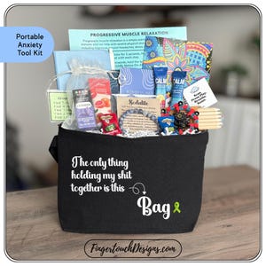 May include: A black tote bag labeled "Portable Anxiety Tool Kit" filled with relaxation items. The bag has the text "The only thing holding my shit together is this Bag" and a green ribbon. Includes lavender, aromatherapy, and mindfulness aids.