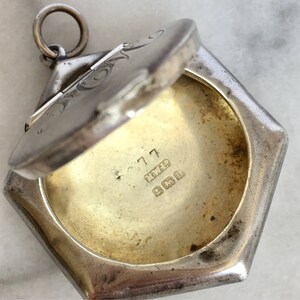 May include: Silver locket with an engraved design on the lid. The locket is open, revealing a blank interior. The locket is marked with the inscription "925" and "C 717".