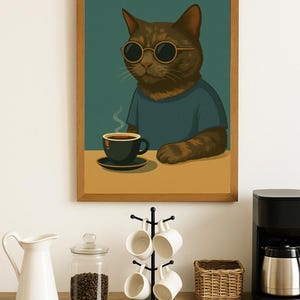 以下が含まれることがあります： サングラスと青いシャツを着た茶色の猫がコーヒーを飲んでいるフレーム入りのアートプリント。 下には、コーヒーメーカー、マグカップ、コーヒー豆の瓶が置かれたカウンターがあります。