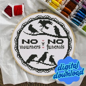 May include: A cross-stitch embroidery hoop with a black and white design. The design features the text "NO MOURNERS, NO FUNERALS" with crow silhouettes. The words "digital download" are in a blue bubble.