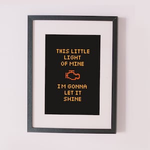 Może przedstawiać: Czarno-biały wydruk w ramie z czarnym tłem i żółtym tekstem, który brzmi "This little light of mine, I'm gonna let it shine." Pixelowa grafika kontrolki silnika samochodu znajduje się w środku wydruku.