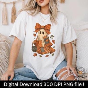 May include: White t-shirt featuring a Halloween ghost design. The ghost is adorned with a patchwork quilt-like outfit, a large orange bow, and a pumpkin-shaped treat basket. Autumn leaves surround the ghost. Text at the bottom reads: Digital Download 300 DPI PNG file!