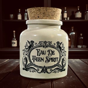 May include: A cream-coloured apothecary jar with a cork stopper. The jar features a black ornate design with the text "Eau De Teen Spirit". The background includes a dark wooden shelf with bottles.