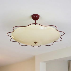 May include: A vintage ceiling light fixture with a cream-colored, scalloped glass shade. The fixture has a dark red metal frame and a matching ceiling mount. The design is reminiscent of mid-century modern styles.