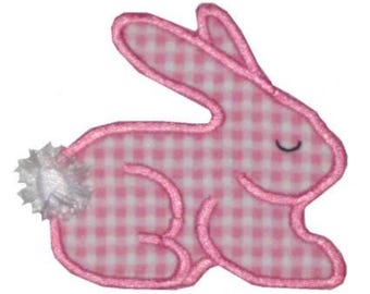 May include: A pink and white gingham bunny applique with a pink outline and a white fluffy tail. The bunny is in a side-facing pose with a closed eye, suitable for Easter or spring-themed crafts.
