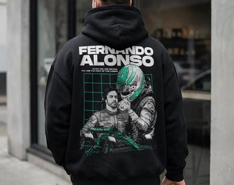 Może przedstawiać: Czarna bluza z kapturem z nadrukiem graficznym na plecach. Wzór zawiera napis "FERNANDO ALONSO" oraz "WHEN YOU ARE SECOND, YOU ARE THE FIRST OF THE LOSERS" nad ilustracją kierowcy wyścigowego i zielonego samochodu wyścigowego.