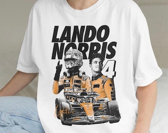 Może przedstawiać: Biały t-shirt z krótkim rękawem z nadrukiem graficznym przedstawiającym Lando Norrisa w kombinezonie wyścigowym i kasku, bolid Formuły 1 oraz numer 4. Napis LANDO NORRIS widnieje dużymi czarnymi literami nad ilustracją kierowcy i samochodu.