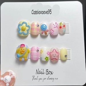 Caja de uñas postizas con dibujos animados, diseño de estrella, pato, flor y caramelo, set de uñas kawaii de colores, caja de uñas bonita