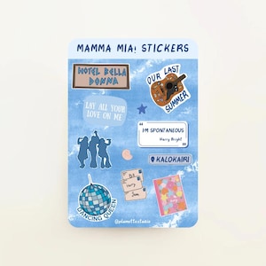 Puede incluir: Una hoja de pegatinas con un fondo azul acuarela. Las pegatinas presentan citas, una guitarra, una bola de discoteca y las palabras "Mamma Mia!" y "Dancing Queen". Otras pegatinas incluyen "Hotel Bella Donna" y "Kalokairi."