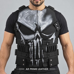 Peut inclure: Un gilet tactique noir arborant un grand motif de crâne peint à la main en blanc sur le devant. Le gilet comprend plusieurs sangles horizontales, des boucles intégrées pour l'équipement et des boutons-pression métalliques. Le texte AR PRIME LEATHER est imprimé en bas.