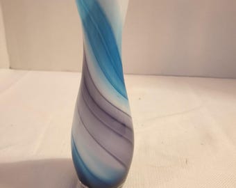 May include: A decorative glass vase with a slender, curved shape. The vase features a swirling pattern of blue, white, and purple hues. The vase is approximately 8 inches tall and has a clear base.