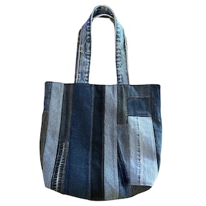 May include: A patchwork denim tote bag. The bag is made from various shades of blue denim, arranged in vertical stripes. It has denim handles and a rectangular shape. Suitable for carrying items.