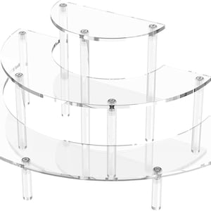 以下が含まれることがあります： 透明なアクリル製の段付きディスプレイスタンド。3つの半円形の棚があり、透明な円筒形の脚で支えられ、シルバーの金具で固定されています。 コレクションや商品を展示するのに最適です。