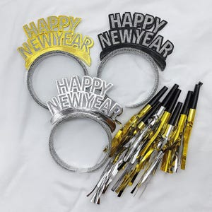 Puede incluir: Un conjunto de artículos para la fiesta de Nochevieja, que incluye tres diademas con "HAPPY NEW YEAR" en purpurina dorada, plateada y negra, y varias cornetas doradas y plateadas con boquillas negras.