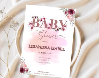 May include: A baby shower invitation with a floral design. The invitation features the words "BABY Shower" in a mauve color, with the name "LYSANDRA ISABEL" below. The date and time are also included. The invitation is decorated with floral accents.