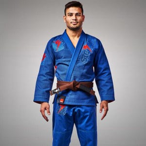 May include: A blue martial arts uniform with red and white embroidered details. The uniform includes a jacket with a wrap closure and a pair of pants. A brown belt is tied around the waist. The uniform is worn by a person.
