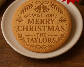 May include: A round, baked cookie with the words "WE WISH YOU A MERRY CHRISTMAS THE TAYLORS" engraved on its surface. The cookie is on a white plate, with a red star-shaped sticker that says "best Gift 2026".