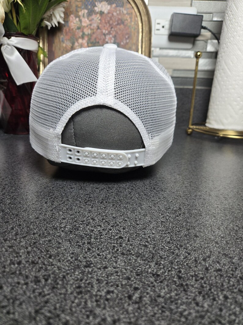 Op de afbeelding: Witte truckerpet met een mesh achterkant en verstelbare druksluiting. De pet heeft een wit voorpaneel en een gebogen klep. De achterkant is van wit mesh voor ventilatie. Geschikt voor casual wear.