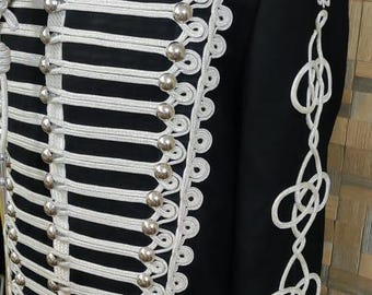 Könnte beinhalten: Schwarze Jacke im Militärstil mit silberfarbenen Verzierungen und Knöpfen. Die Jacke hat weiße Seildetails an der Vorderseite, am Kragen und an den Ärmeln. Ein formelles Kleidungsstück mit klassischem Design.