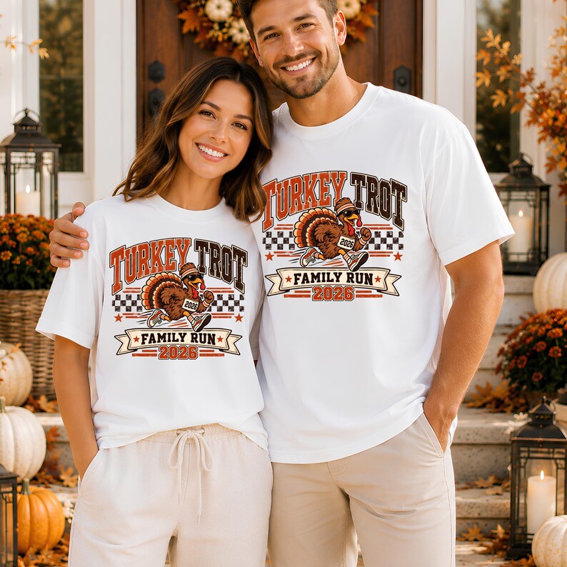 May include: Two white t-shirts featuring a graphic print of a turkey wearing sunglasses and sneakers. The text reads Turkey Trot Family Run 2026. The design includes a checkered pattern, stars, and orange and brown lettering on the front.