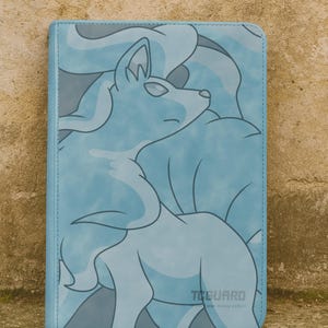 May include: A light blue folio case featuring a stylized illustration of a fox-like creature. The design is in shades of blue and gray. The text "TCGGUARD" is visible on the bottom right corner.