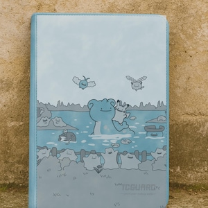 Puede incluir: Un archivador de tarjetas azul claro con una ilustración de dibujos animados de personajes en una masa de agua. El archivador tiene un borde azul claro y el texto "TCGUARD" en la parte inferior.