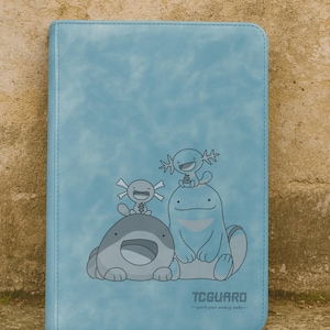 Puede incluir: Una carpeta de tarjetas rectangular de color azul claro con un gráfico impreso de tres criaturas de dibujos animados. El diseño incluye dos pequeñas figuras tipo ajolote y una criatura más grande y redondeada. El texto TCGUARD aparece abajo.