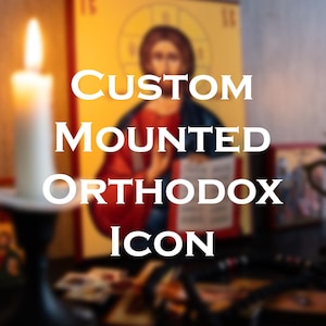 Op de afbeelding: Een gemonteerd orthodox icoon met een religieuze figuur in rode en blauwe gewaden die een boek vasthoudt, met een brandende witte kaars op de voorgrond. De tekst CUSTOM MOUNTED ORTHODOX ICON staat in witte hoofdletters in het midden.