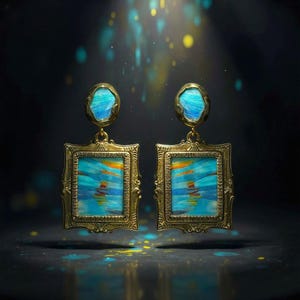 May include: A pair of gold-toned earrings featuring a rectangular frame with an ornate border. Each earring contains a central panel with blue, orange, and yellow brushstroke patterns. Above the rectangle is a small, irregular oval blue stone.