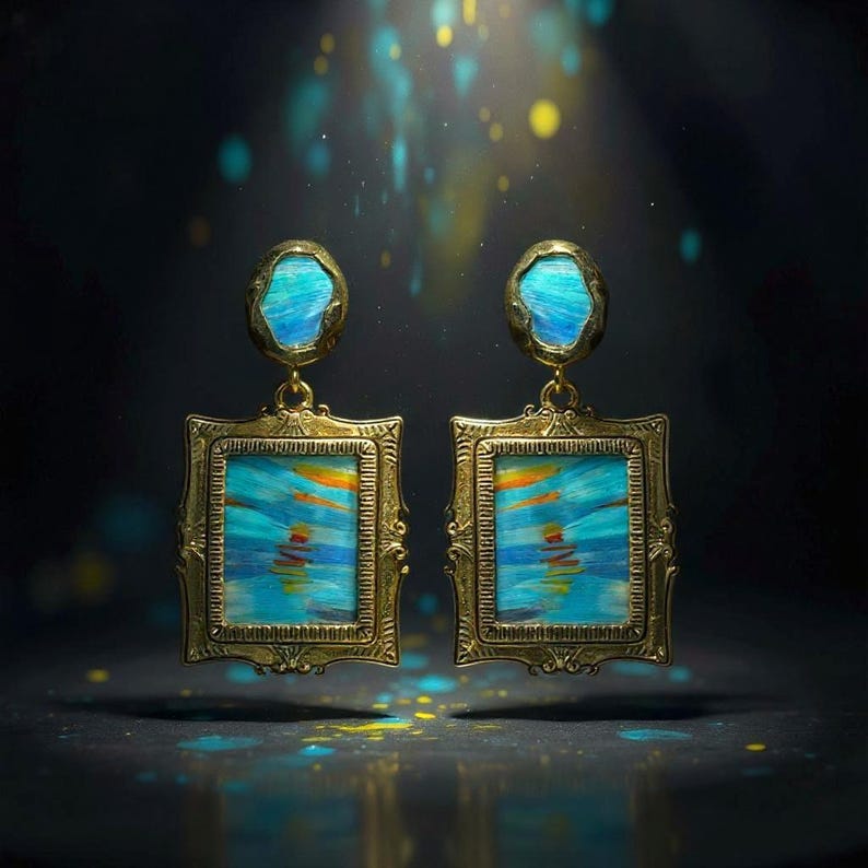 May include: A pair of gold-toned earrings featuring a rectangular frame with an ornate border. Each earring contains a central panel with blue, orange, and yellow brushstroke patterns. Above the rectangle is a small, irregular oval blue stone.