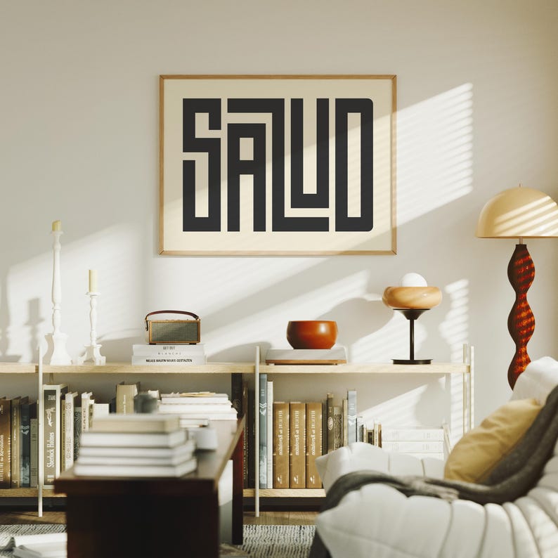 Puede incluir: Un cuadro enmarcado con la palabra "SALUD" en letras negras y gruesas. La obra de arte cuelga sobre una estanter&iacute;a con libros, una peque&ntilde;a radio y un cuenco decorativo. La habitaci&oacute;n tiene una est&eacute;tica moderna y minimalista.