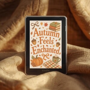Pode incluir: Um leitor de e-books Kindle preto exibindo um gráfico na tela com o texto Autumn Feels Enchanted. A ilustração apresenta uma pilha de livros, bolotas, folhas de outono, uma abóbora, uma caneca fumegante e um cobertor xadrez.