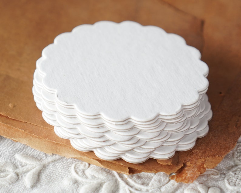 May include: A stack of white scalloped paper doilies. The doilies are round and have a delicate, lacy edge.