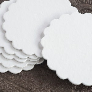May include: A stack of white scalloped paper circles, perfect for crafting or adding a touch of elegance to your projects.