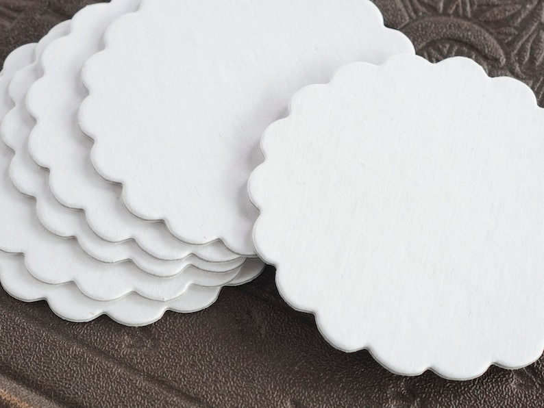 May include: A stack of white scalloped paper circles, perfect for crafting or adding a touch of elegance to your projects.