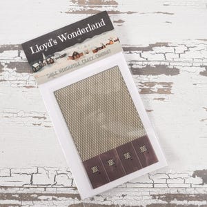 May include: A white package with a brown and white patterned design. The package has the text "Lloyd's Wonderland" and "Small Miniature Craft Company" printed on it. The package contains a miniature building with a brown roof and white walls.