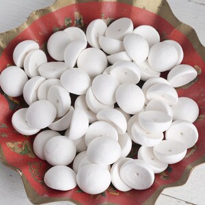 Puede incluir: Un bol lleno de formas de manualidades redondas y blancas de espuma. El bol es rojo con ribete dorado y un patrón floral.