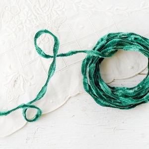 May include: A spool of green velvet pipe cleaners. The pipe cleaners are coiled and ready to be used for crafts.