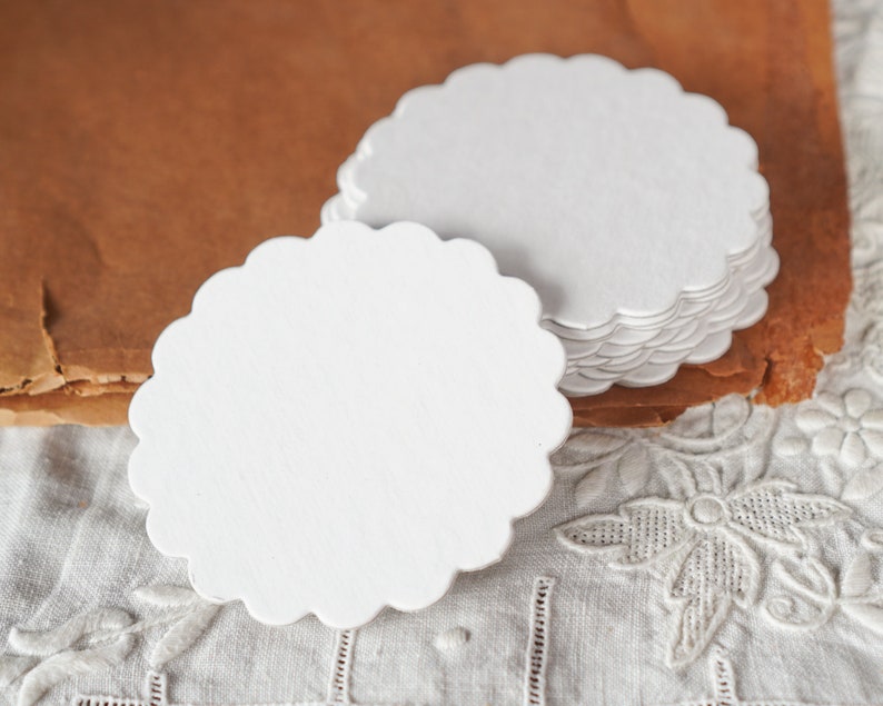 May include: A stack of white scalloped paper circles, perfect for crafting or adding a touch of elegance to your table setting.