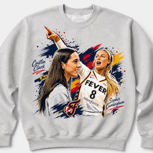 Op de afbeelding: Een lichtgrijs sweatshirt met ronde hals en een grafische print van basketbalspelers Caitlin Clark en Sophie Cunningham. Het ontwerp bevat de tekst FEVER 8, Salesforce en de namen van de spelers tegen een achtergrond van blauwe, gele en rode verfspatten.